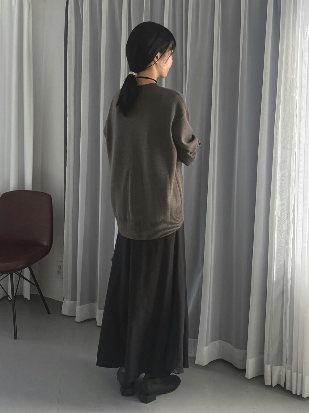 グレー系のニット/セーター、ブラック系のスカートを着用したレディースの秋コーディネートの3枚目の写真