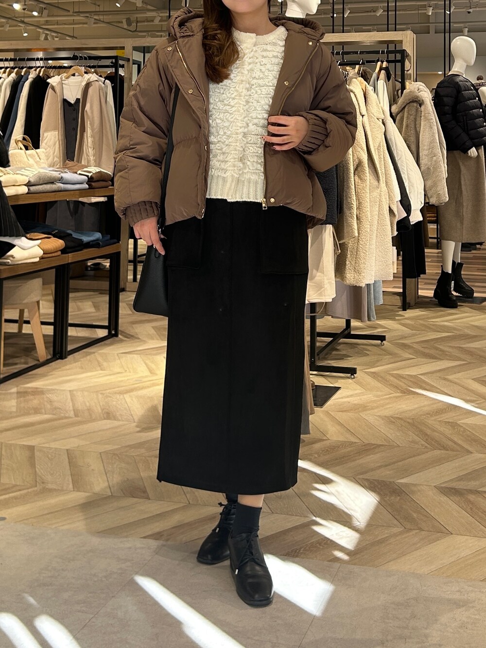 ホワイト系のカーディガン/ボレロ、ブラウン系のダウンジャケット/コート、ブラック系のスカートを着用したレディースの冬コーディネートの4枚目の写真