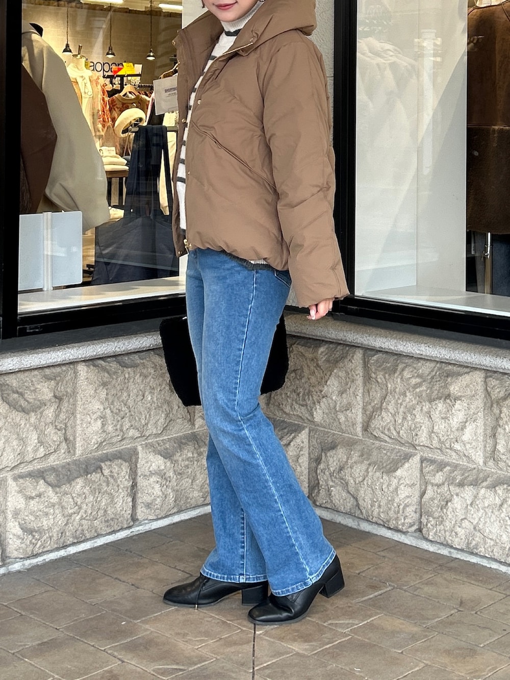 ホワイト系のニット/セーター、ブルー系のデニムパンツ、ブラック系のブーツを着用したレディースの冬コーディネートの2枚目の写真