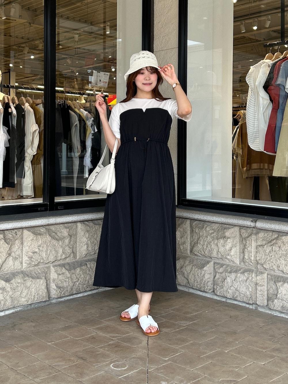 ブラック系のワンピース、ホワイト系のサンダル、ホワイト系のキャップを着用したレディースの夏コーディネートの4枚目の写真