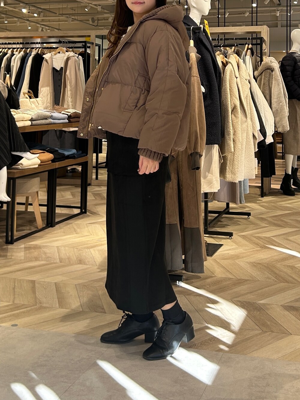 ホワイト系のカーディガン/ボレロ、ブラウン系のダウンジャケット/コート、ブラック系のスカートを着用したレディースの冬コーディネートの2枚目の写真