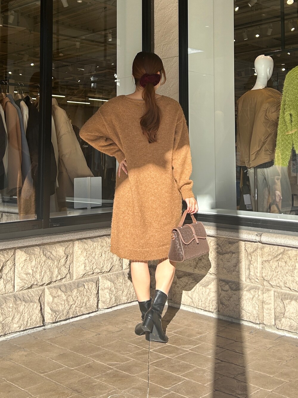 ベージュ系のチュニック、ブラック系のブーツを着用したレディースの冬コーディネートの3枚目の写真