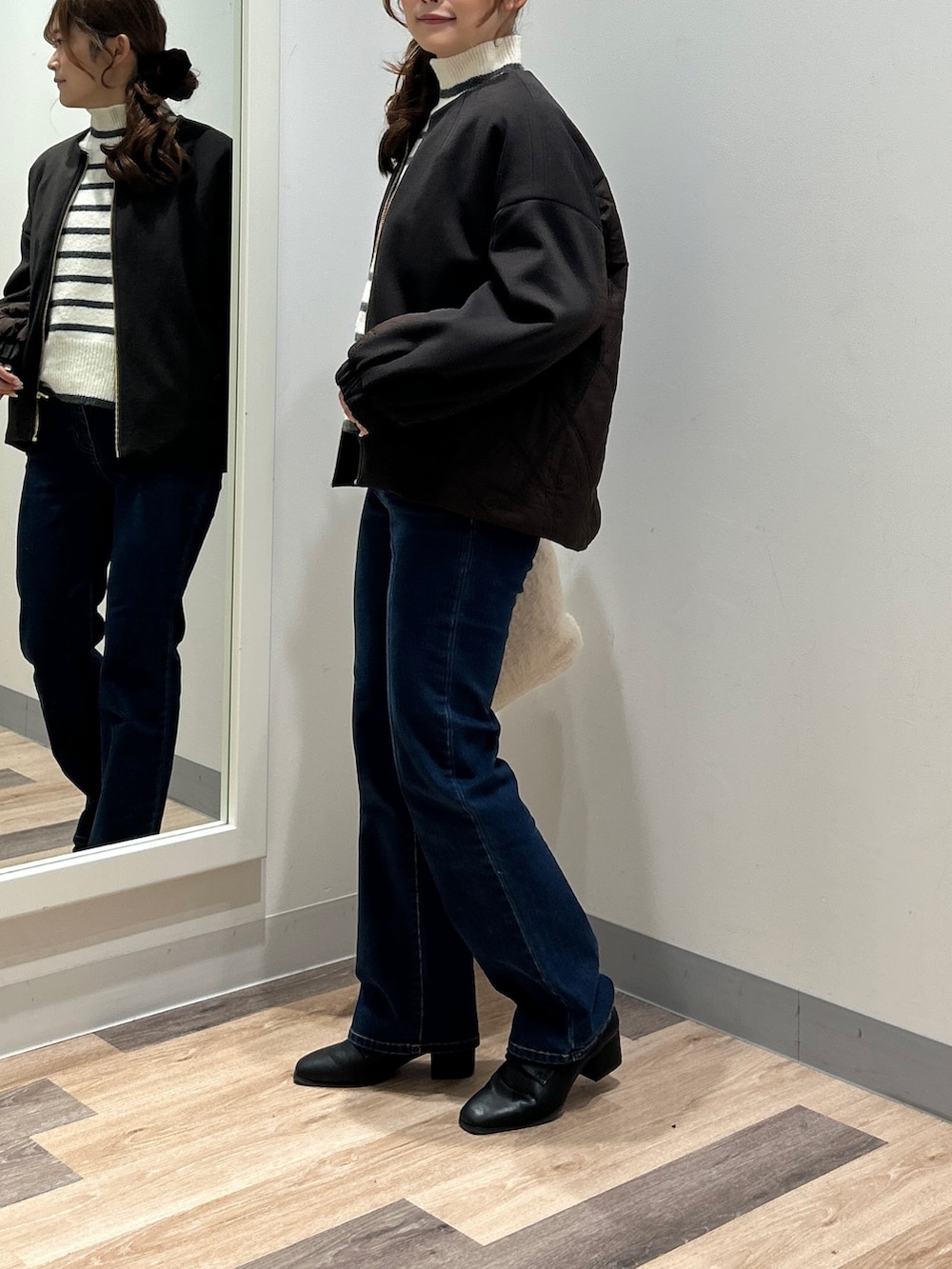 ホワイト系のニット/セーター、ブルー系のデニムパンツ、ブラック系のブーツを着用したレディースの秋コーディネートの2枚目の写真