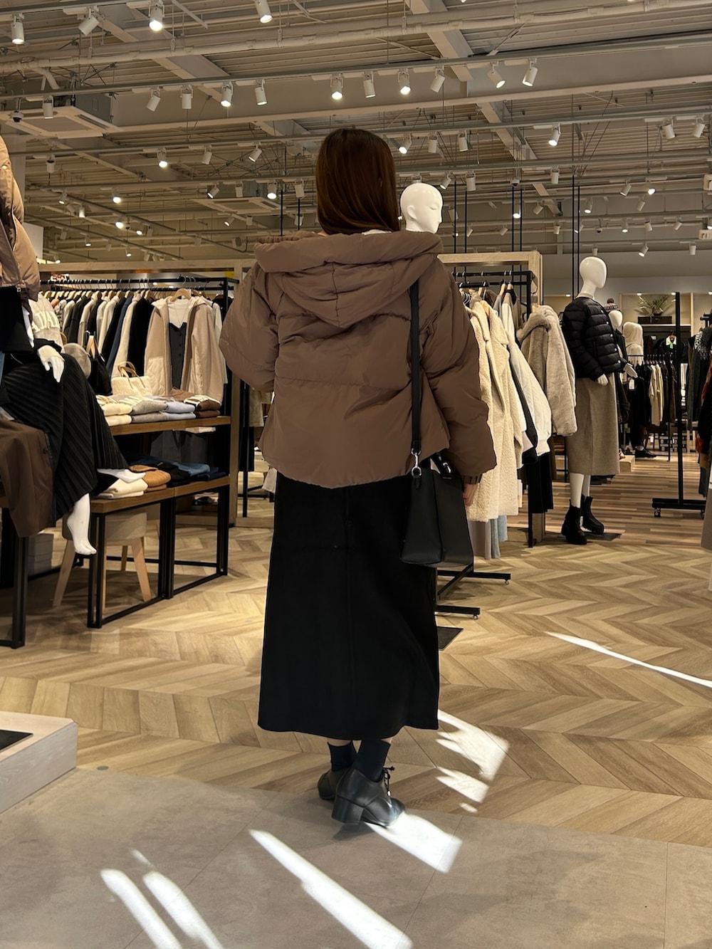 ホワイト系のカーディガン/ボレロ、ブラウン系のダウンジャケット/コート、ブラック系のスカートを着用したレディースの冬コーディネートの3枚目の写真