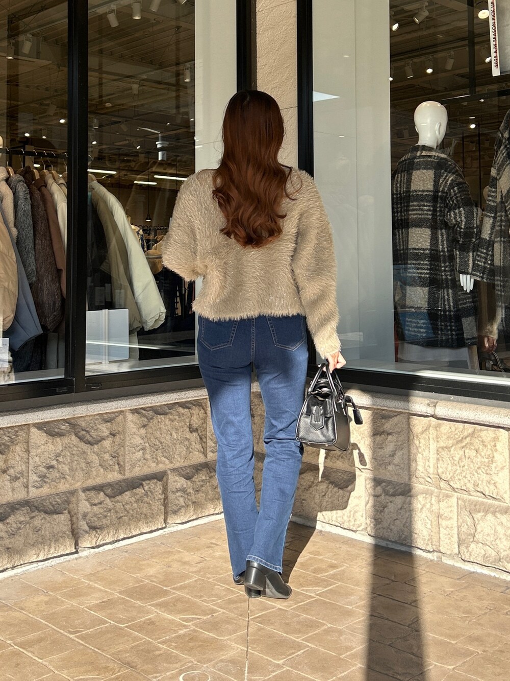 ベージュ系のカーディガン/ボレロ、ホワイト系のニット/セーター、ブルー系のデニムパンツを着用したレディースの冬コーディネートの3枚目の写真