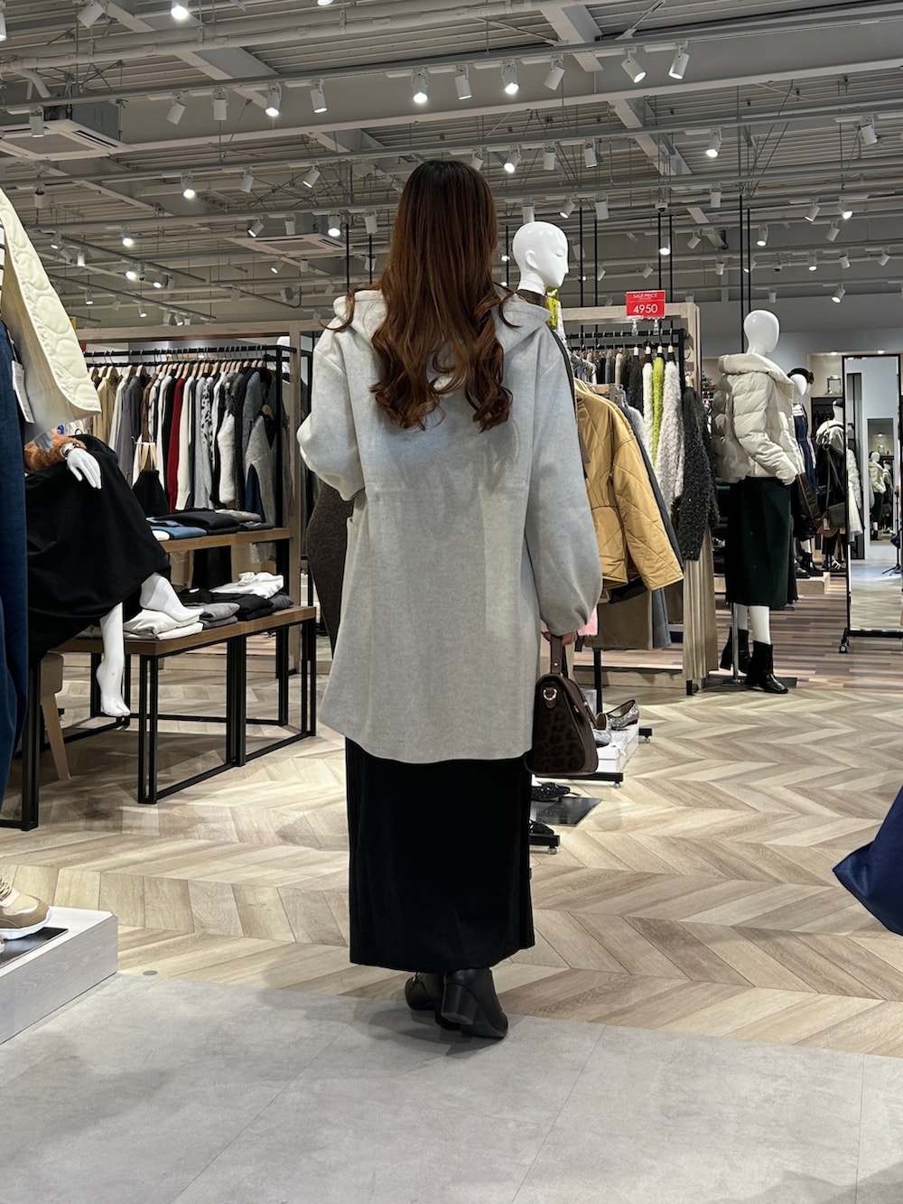 ホワイト系のニット/セーター、グレー系のスカート、ブラック系のブーツを着用したレディースの冬コーディネートの3枚目の写真