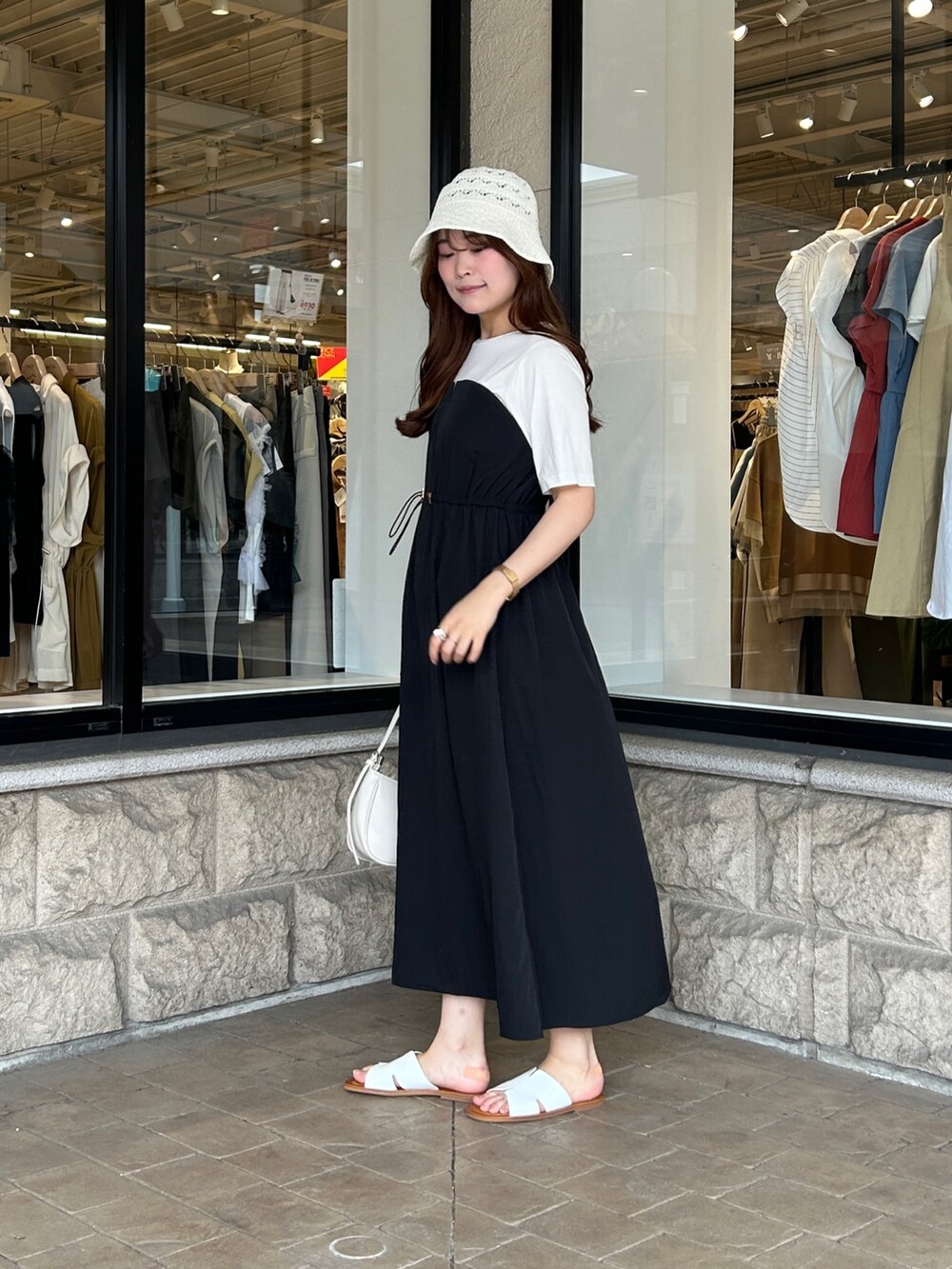 ブラック系のワンピース、ホワイト系のサンダル、ホワイト系のキャップを着用したレディースの夏コーディネートの2枚目の写真