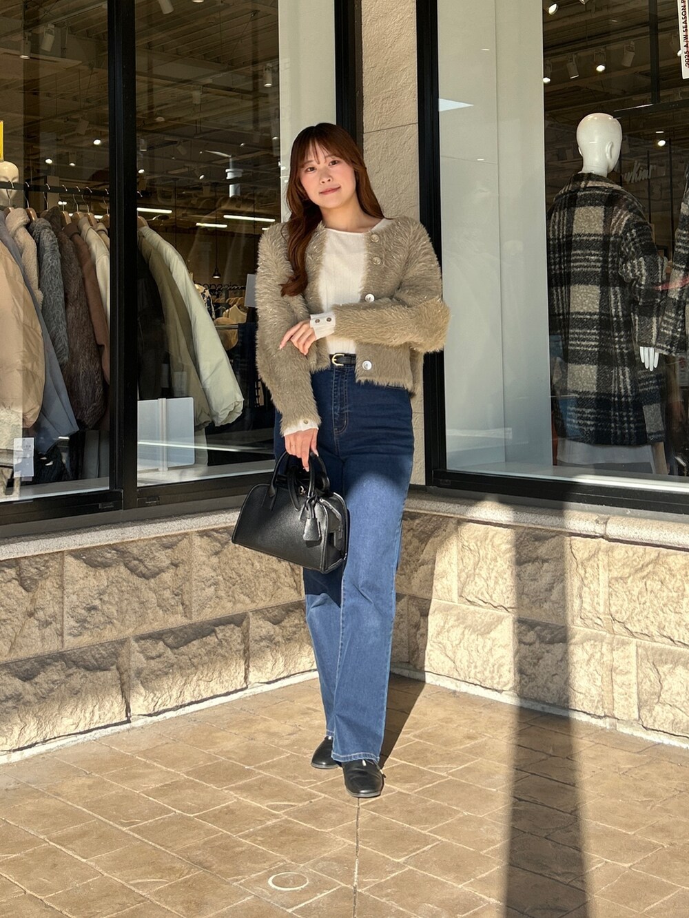 ベージュ系のカーディガン/ボレロ、ホワイト系のニット/セーター、ブルー系のデニムパンツを着用したレディースの冬コーディネートの4枚目の写真