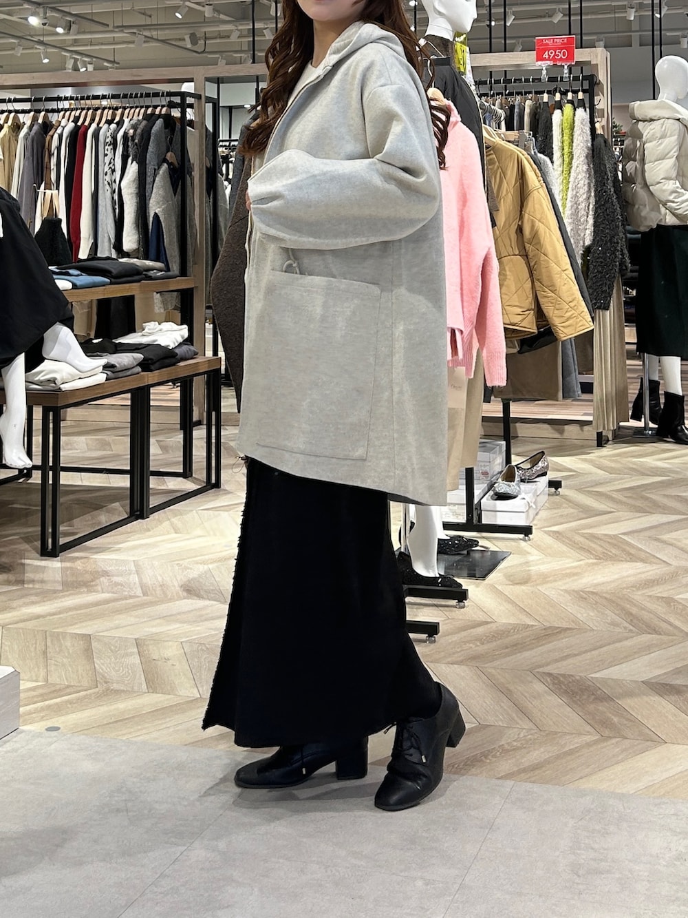 ホワイト系のニット/セーター、グレー系のスカート、ブラック系のブーツを着用したレディースの冬コーディネートの2枚目の写真