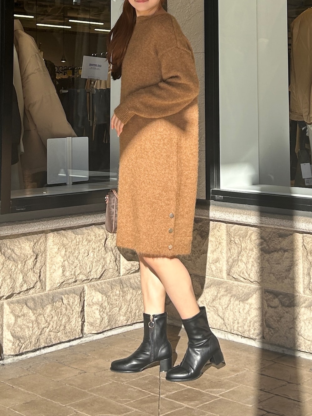 ベージュ系のチュニック、ブラック系のブーツを着用したレディースの冬コーディネートの2枚目の写真