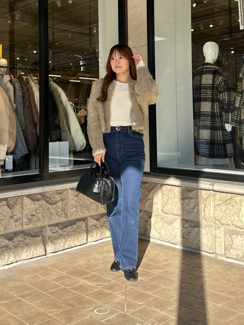 ベージュ系のカーディガン/ボレロ、ホワイト系のニット/セーター、ブルー系のデニムパンツを着用したレディースの冬コーディネートの5枚目の写真