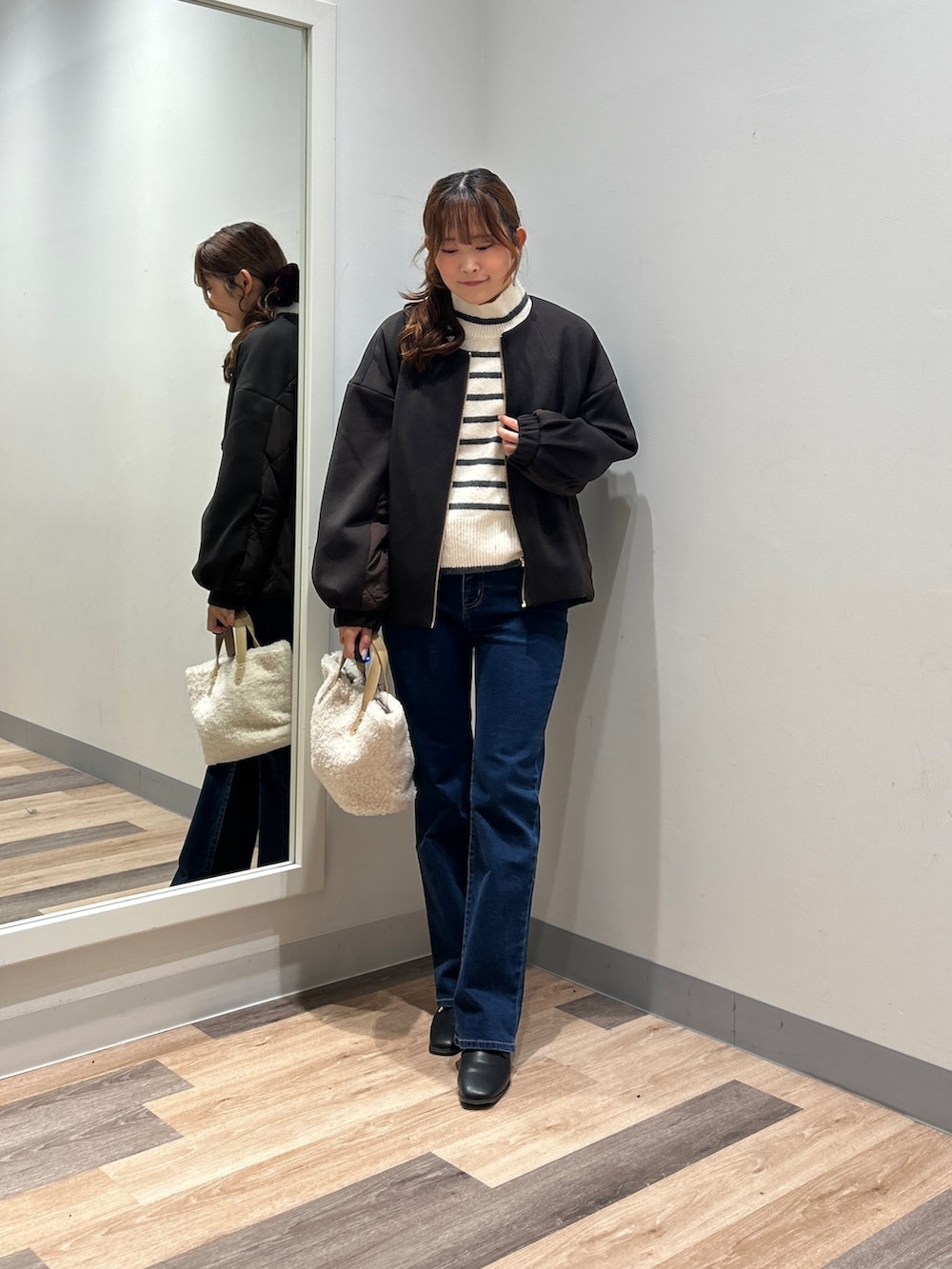 ホワイト系のニット/セーター、ブルー系のデニムパンツ、ブラック系のブーツを着用したレディースの秋コーディネートの4枚目の写真