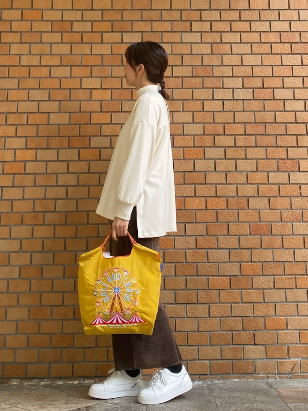 ホワイト系のTシャツ/カットソー、イエロー系のトートバッグ、ブラウン系のスカートを着用したレディースの冬コーディネートの3枚目の写真