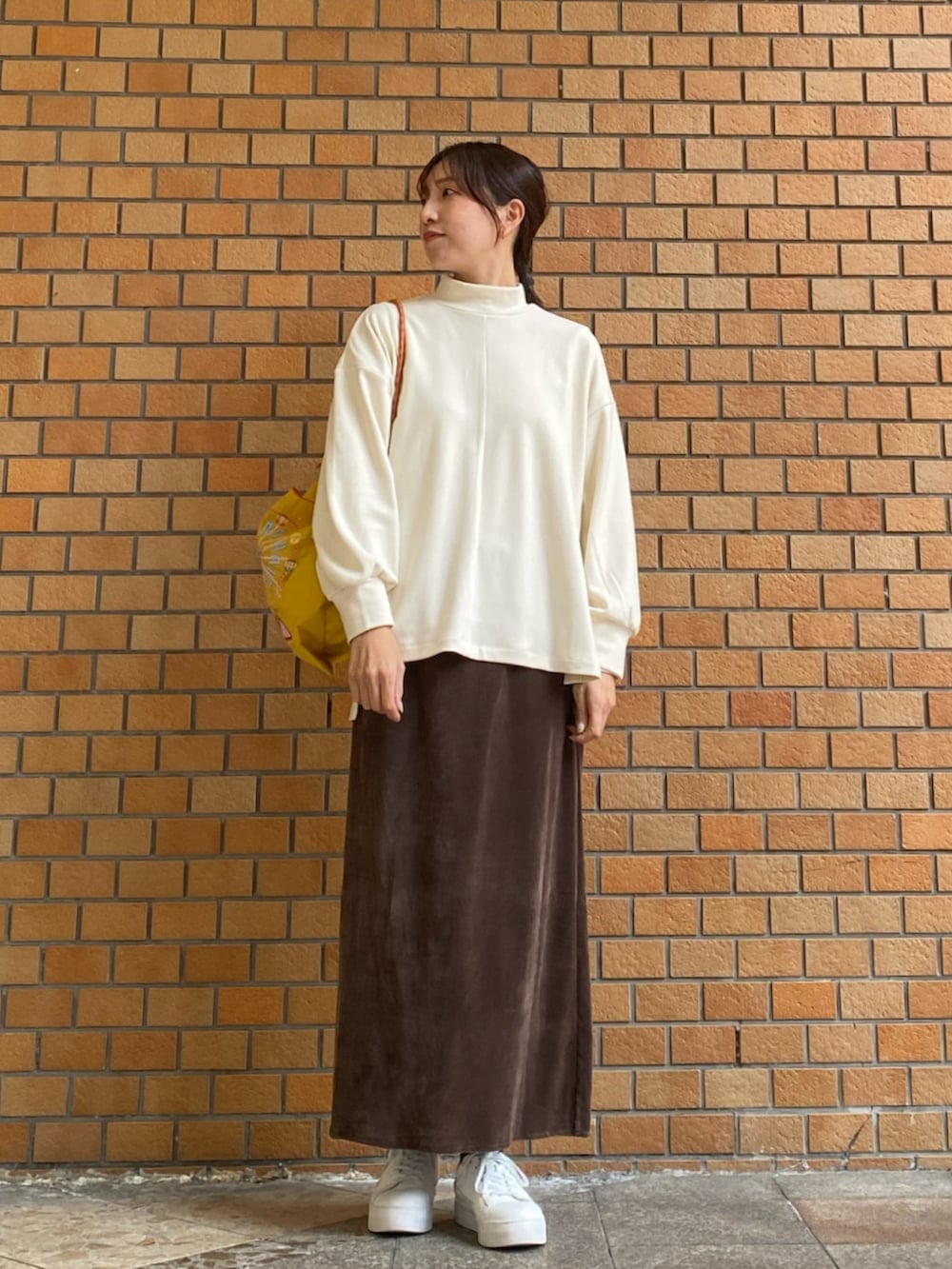 ホワイト系のTシャツ/カットソー、イエロー系のトートバッグ、ブラウン系のスカートを着用したレディースの冬コーディネートの2枚目の写真