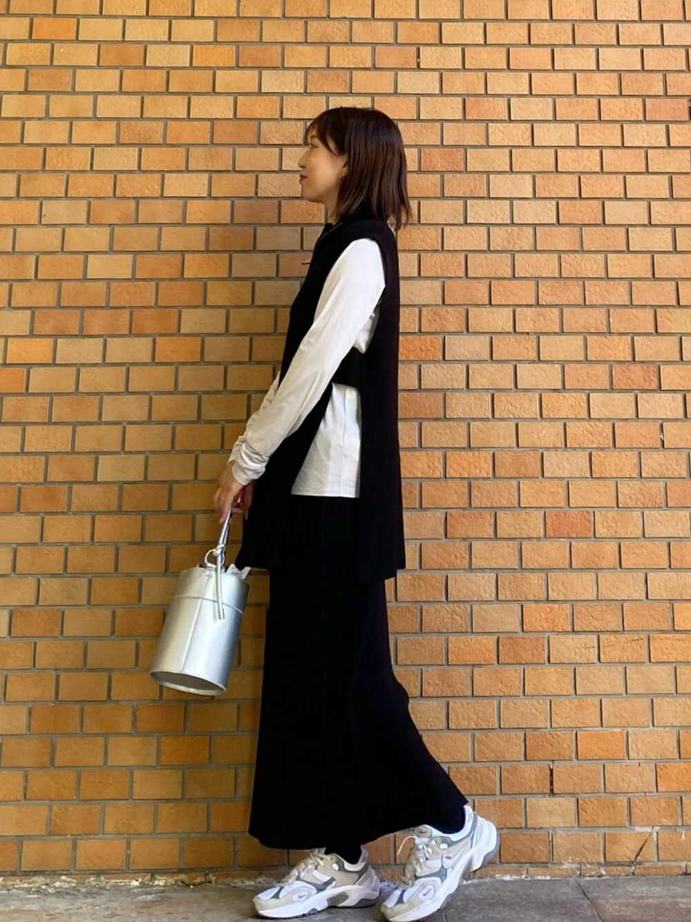 ブラック系のワンピース、ホワイト系のTシャツ/カットソー、シルバー系のショルダーバッグを着用したレディースの秋コーディネートの2枚目の写真