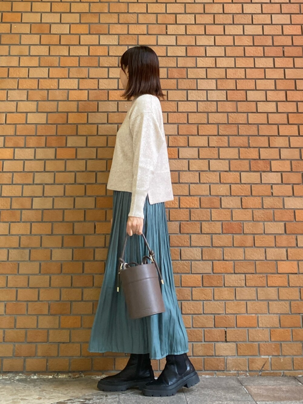 ホワイト系のニット/セーター、グリーン系のスカート、ブラウン系のショルダーバッグを着用したレディースの冬コーディネートの3枚目の写真