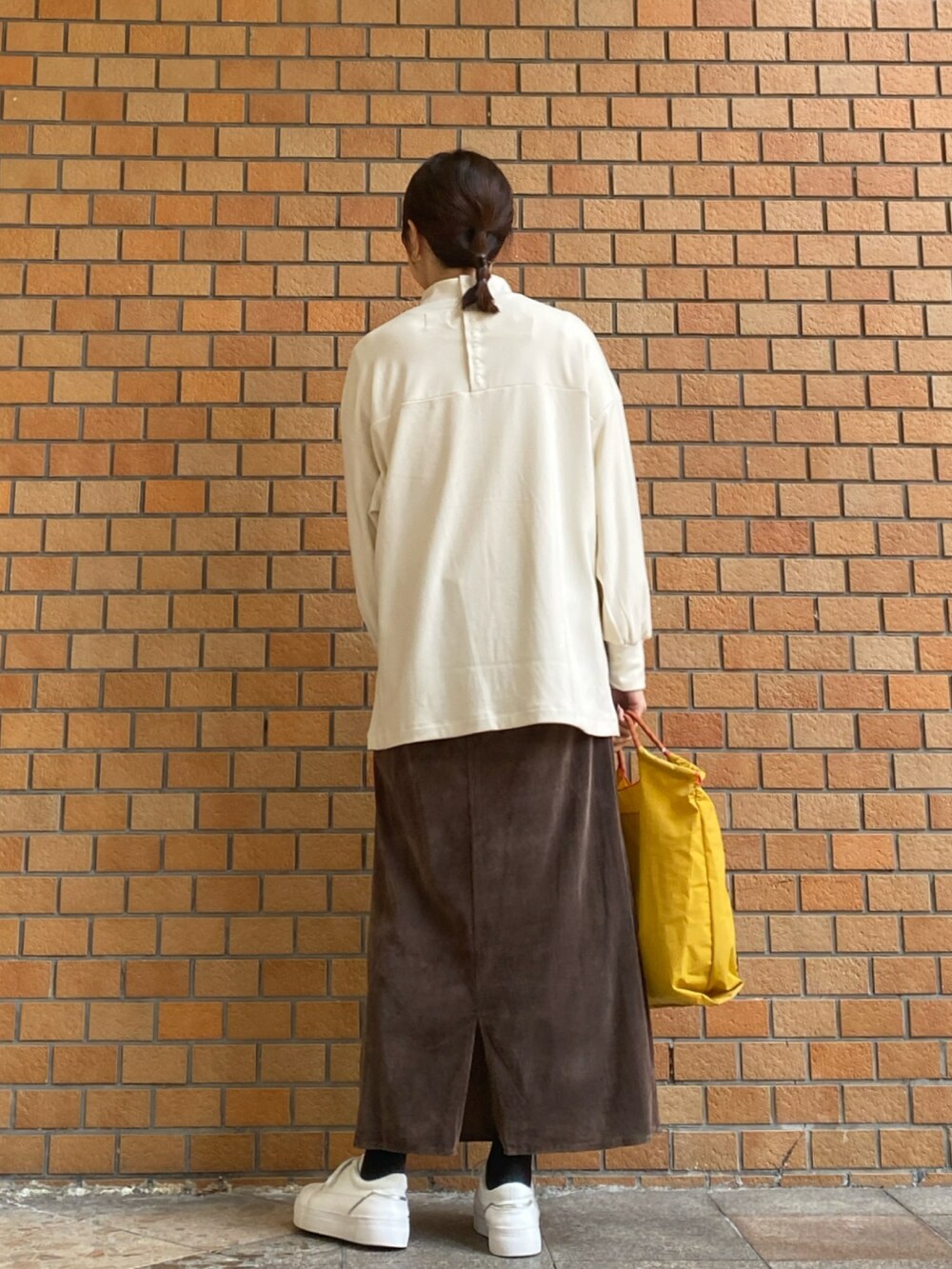 ホワイト系のTシャツ/カットソー、イエロー系のトートバッグ、ブラウン系のスカートを着用したレディースの冬コーディネートの6枚目の写真