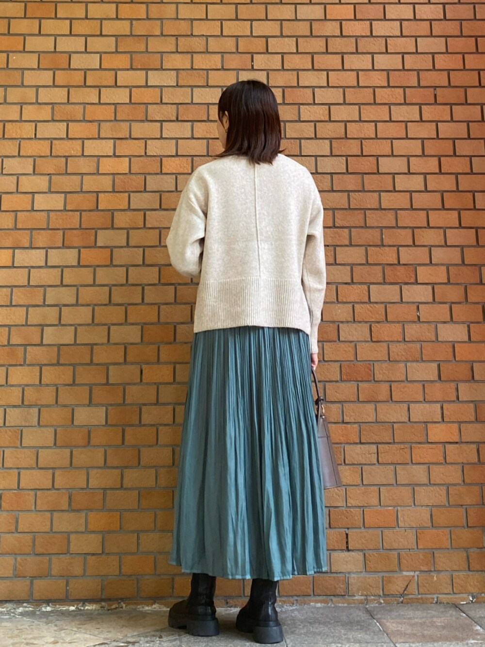 ホワイト系のニット/セーター、グリーン系のスカート、ブラウン系のショルダーバッグを着用したレディースの冬コーディネートの4枚目の写真