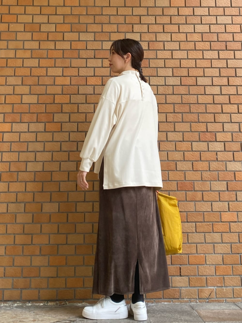 ホワイト系のTシャツ/カットソー、イエロー系のトートバッグ、ブラウン系のスカートを着用したレディースの冬コーディネートの4枚目の写真