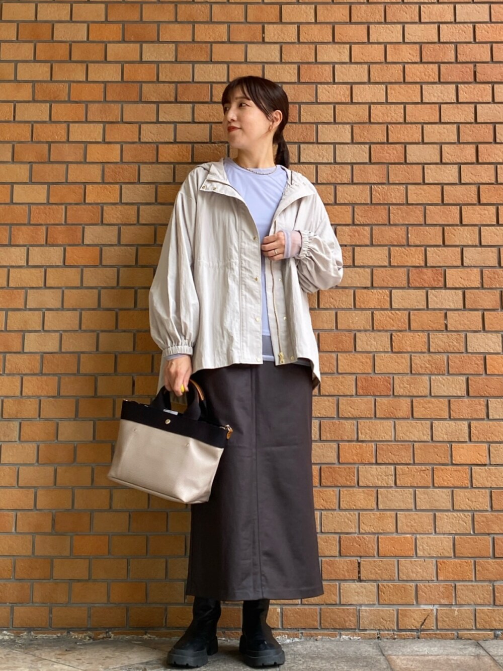 ブルー系のTシャツ/カットソー、ブラウン系のスカート、ベージュ系のマウンテンパーカーを着用したレディースの秋コーディネートの2枚目の写真