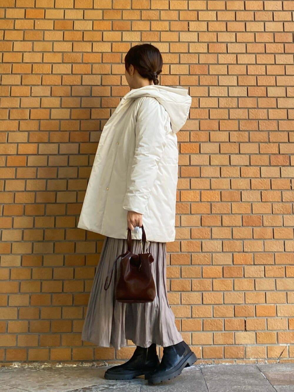 グレー系のニット/セーター、ホワイト系のダウンジャケット/コート、ベージュ系のスカートを着用したレディースの冬コーディネートの2枚目の写真