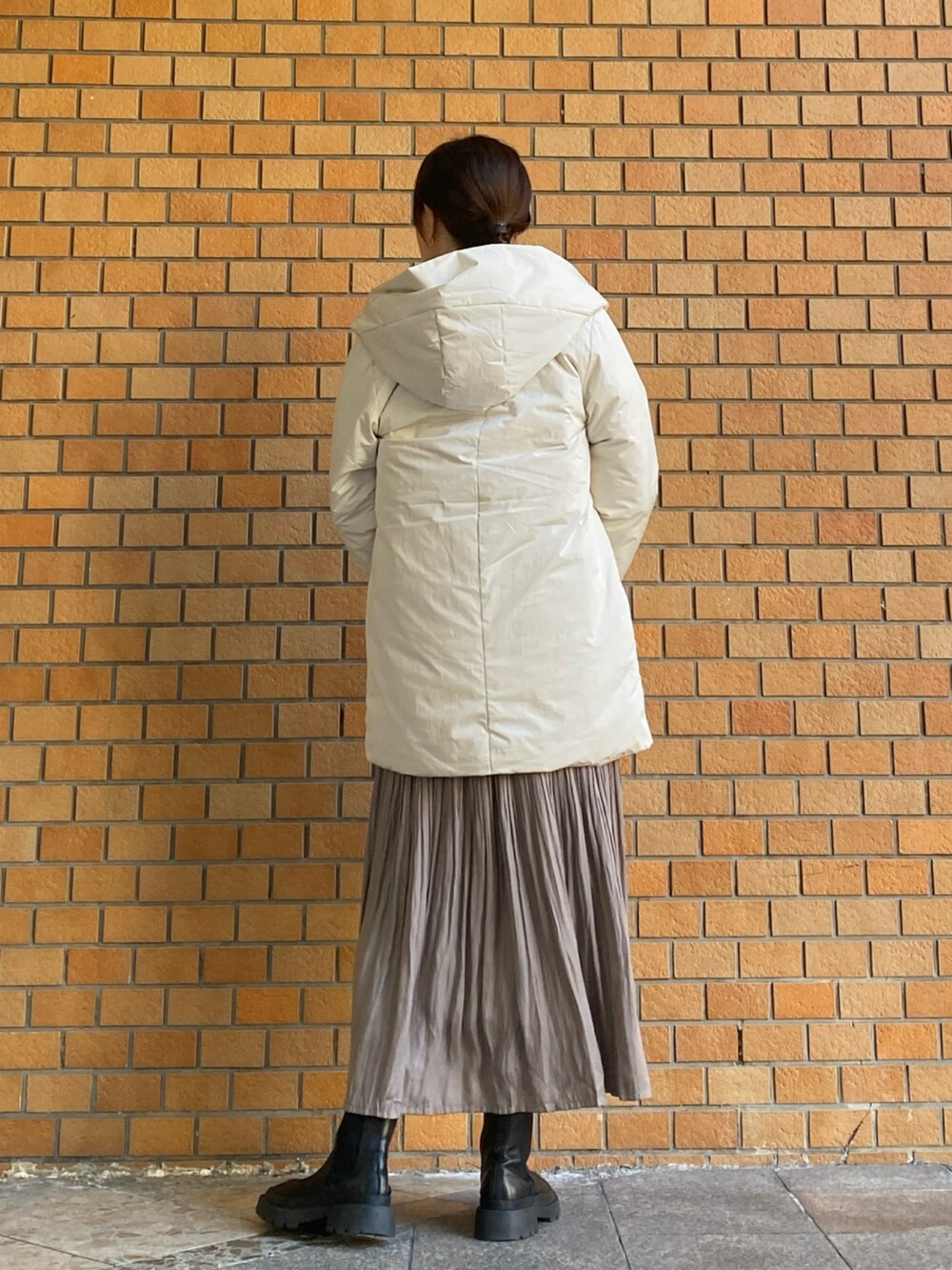 グレー系のニット/セーター、ホワイト系のダウンジャケット/コート、ベージュ系のスカートを着用したレディースの冬コーディネートの3枚目の写真