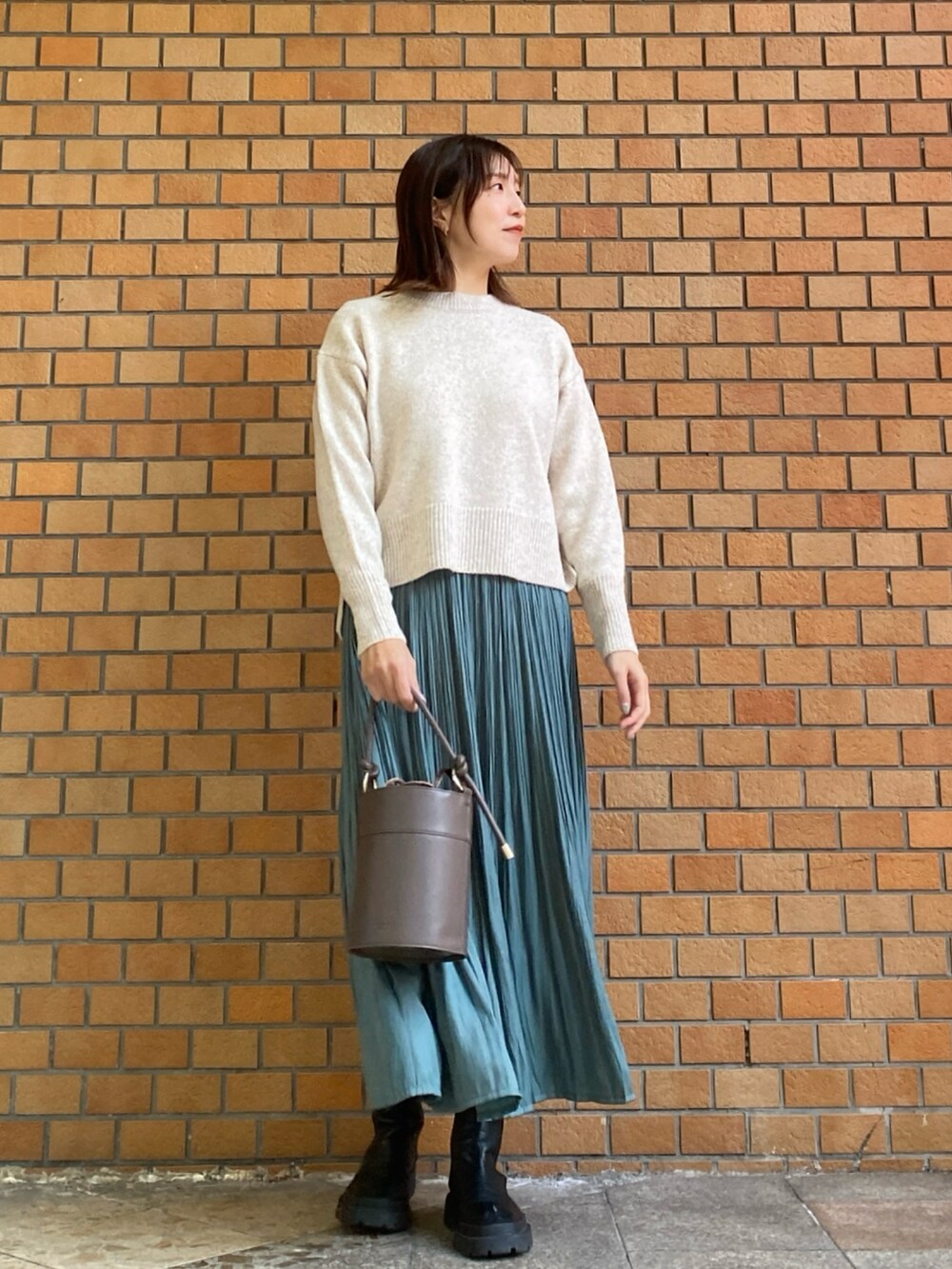 ホワイト系のニット/セーター、グリーン系のスカート、ブラウン系のショルダーバッグを着用したレディースの冬コーディネートの2枚目の写真