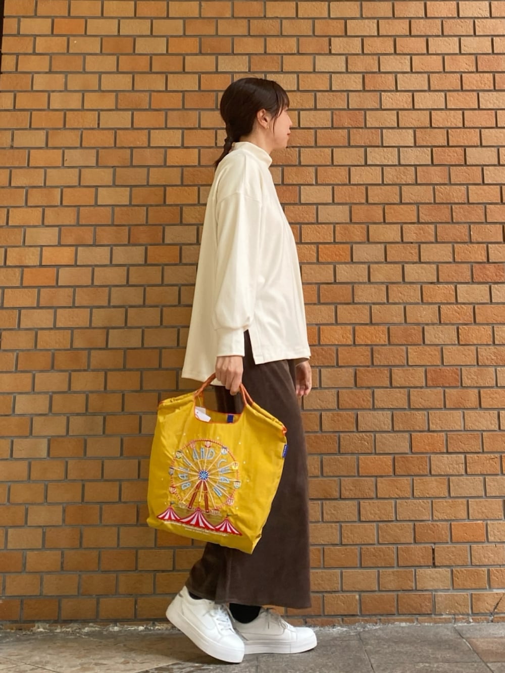 ホワイト系のTシャツ/カットソー、イエロー系のトートバッグ、ブラウン系のスカートを着用したレディースの冬コーディネートの5枚目の写真