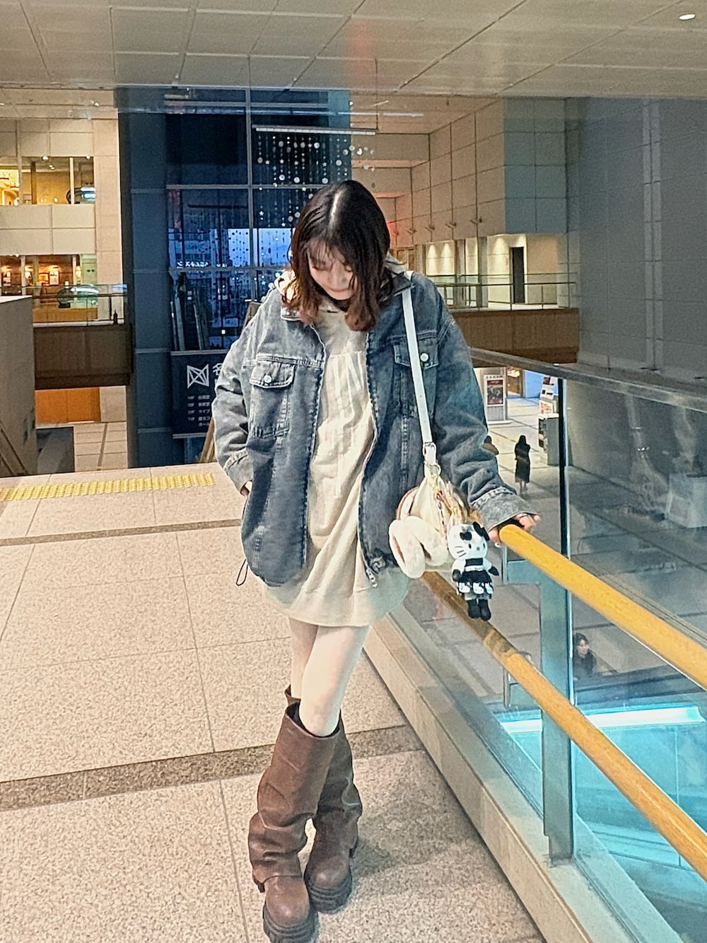 ベージュ系のパーカー、ブルー系のデニムジャケット、ホワイト系のショルダーバッグを着用したレディースの冬コーディネートの3枚目の写真