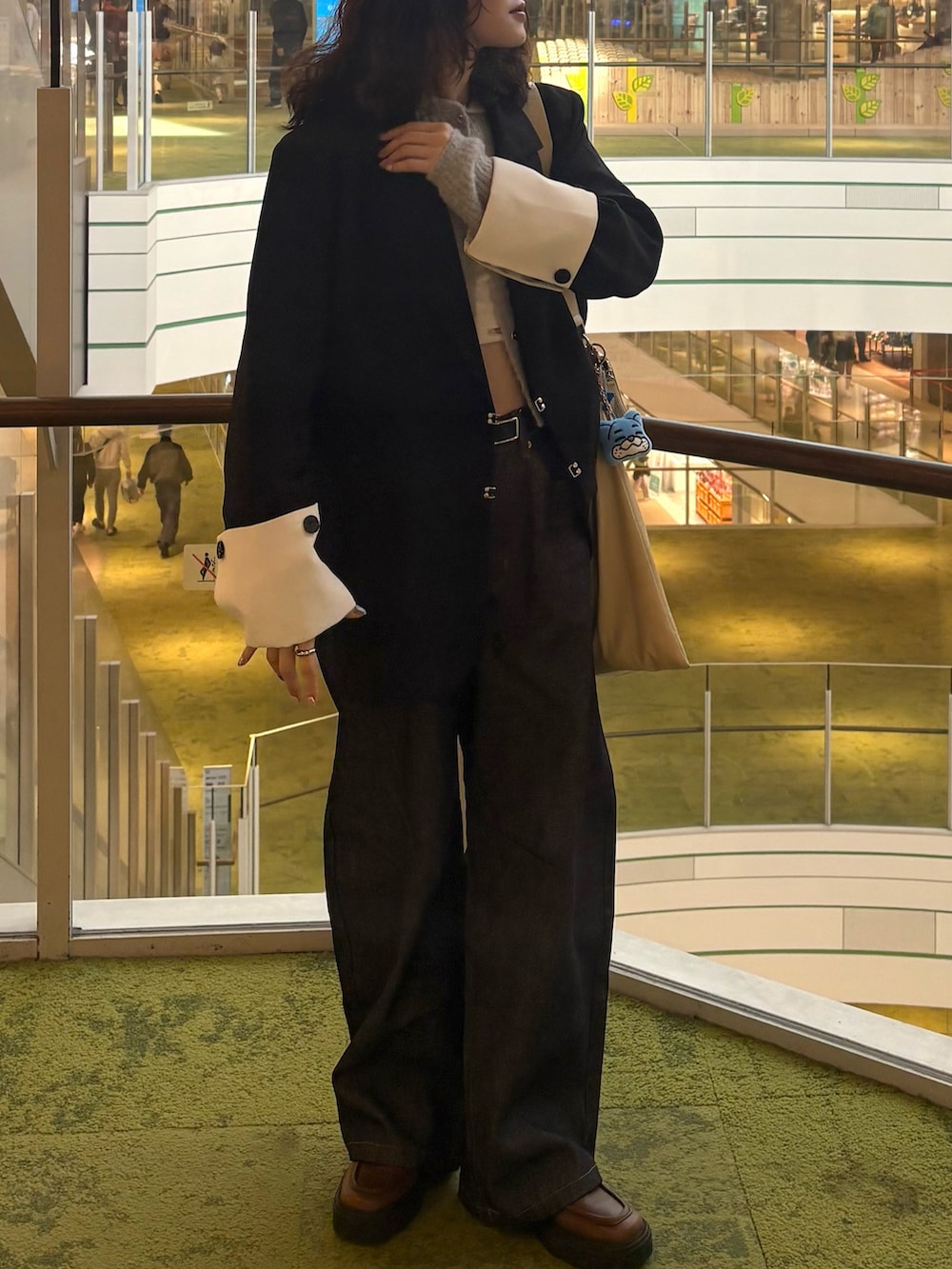 ブルー系のデニムパンツ、ブラウン系のブーツ、ホワイト系のキャミソールを着用したレディースの春コーディネートの2枚目の写真