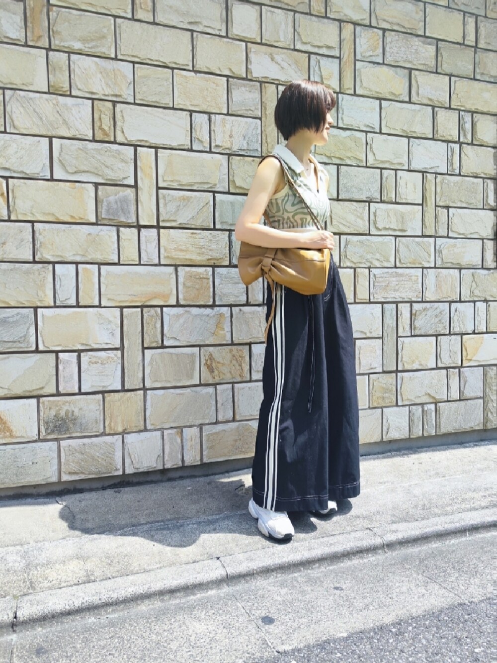 ブラック系のチノパンツ、ホワイト系のタンクトップ、ブラウン系のショルダーバッグを着用したレディースの夏コーディネートの2枚目の写真
