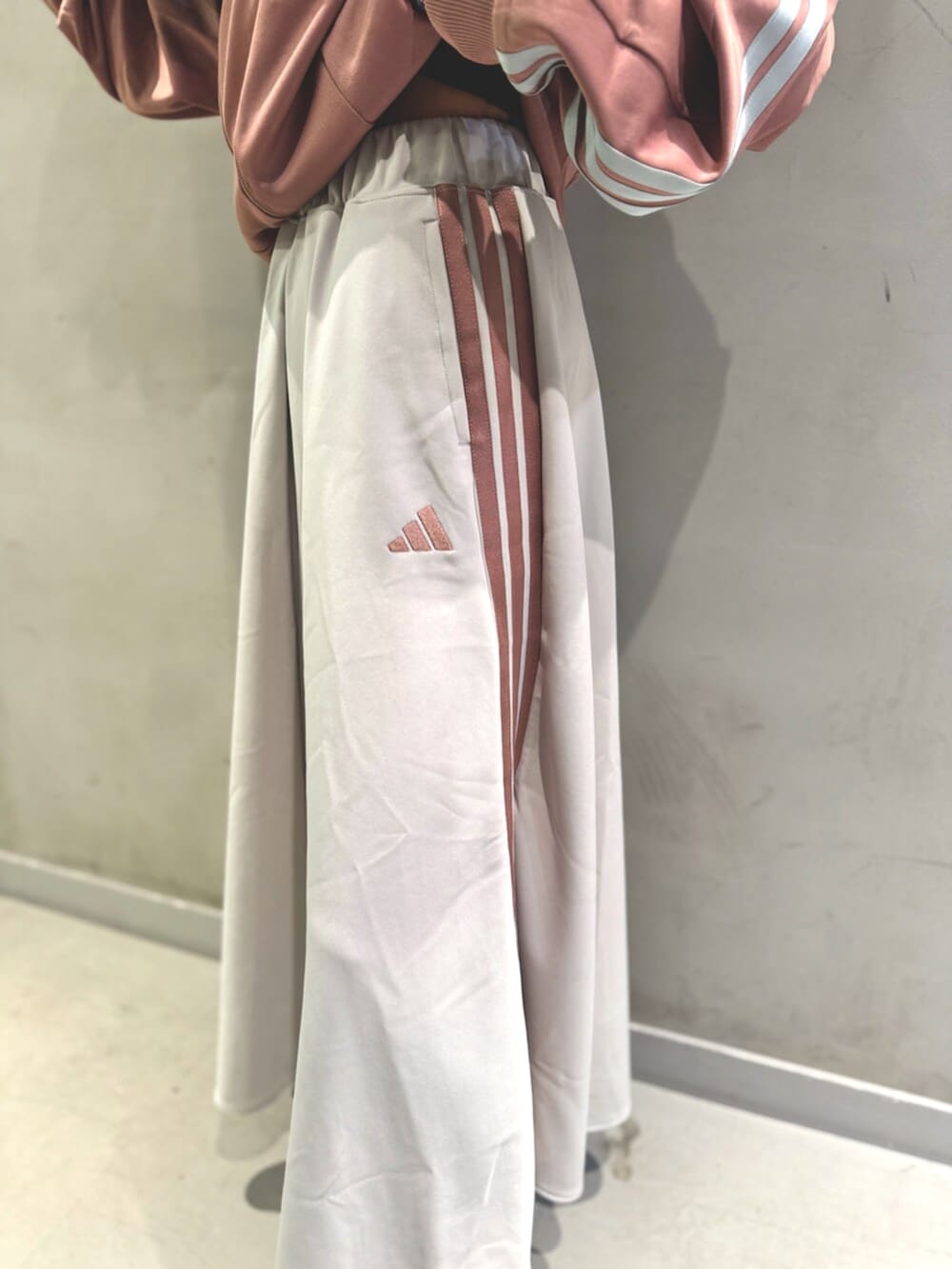 レッド系のジャージ、ホワイト系のスカート、ブラック系のショルダーバッグを着用したレディースの秋コーディネートの4枚目の写真