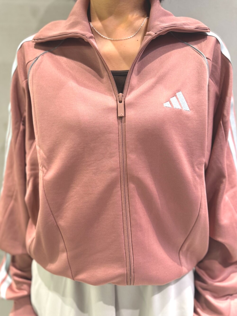 レッド系のジャージ、ホワイト系のスカート、ブラック系のショルダーバッグを着用したレディースの秋コーディネートの3枚目の写真