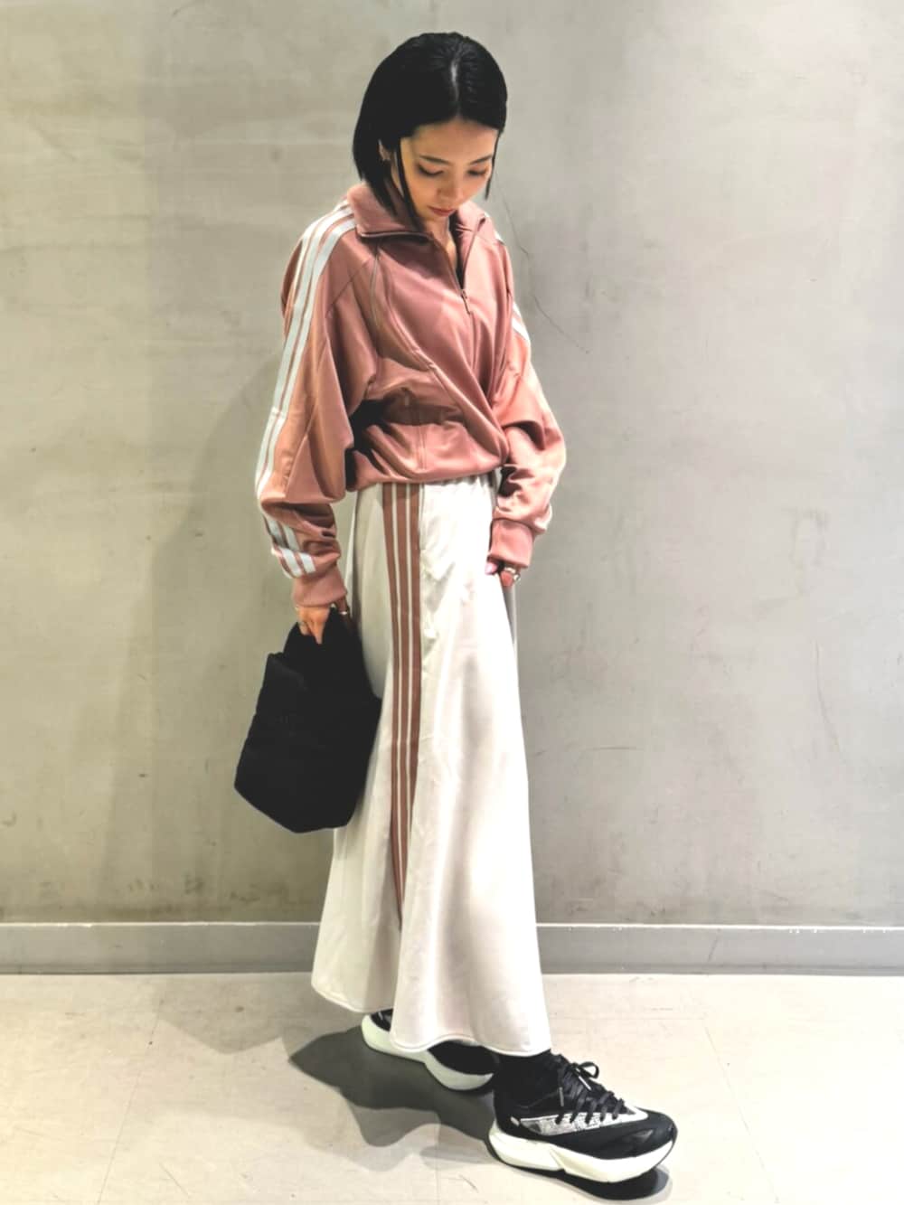 レッド系のジャージ、ホワイト系のスカート、ブラック系のショルダーバッグを着用したレディースの秋コーディネートの2枚目の写真