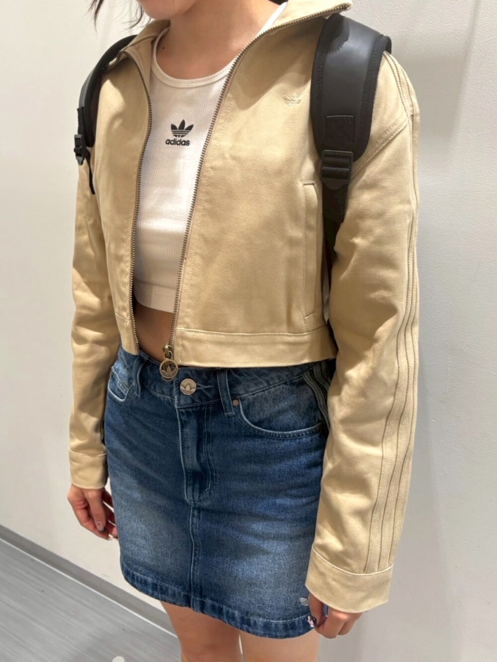 ブラウン系のスニーカー、ベージュ系のナイロンジャケット、ブルー系のデニムスカートを着用したレディースの秋コーディネートの3枚目の写真