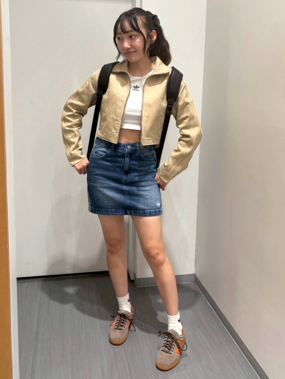 ブラウン系のスニーカー、ベージュ系のナイロンジャケット、ブルー系のデニムスカートを着用したレディースの秋コーディネートの2枚目の写真