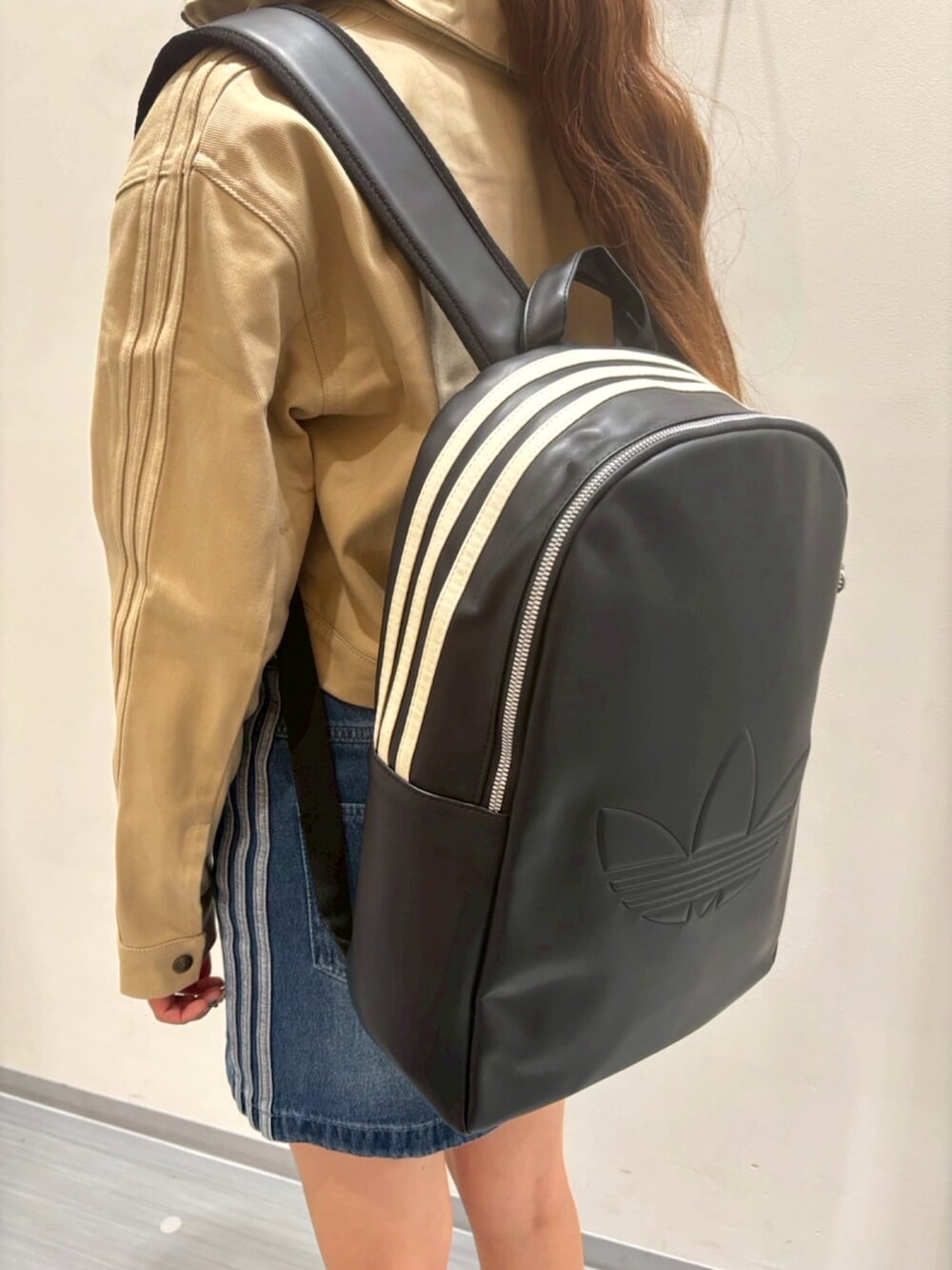 ブラウン系のスニーカー、ベージュ系のナイロンジャケット、ブルー系のデニムスカートを着用したレディースの秋コーディネートの4枚目の写真