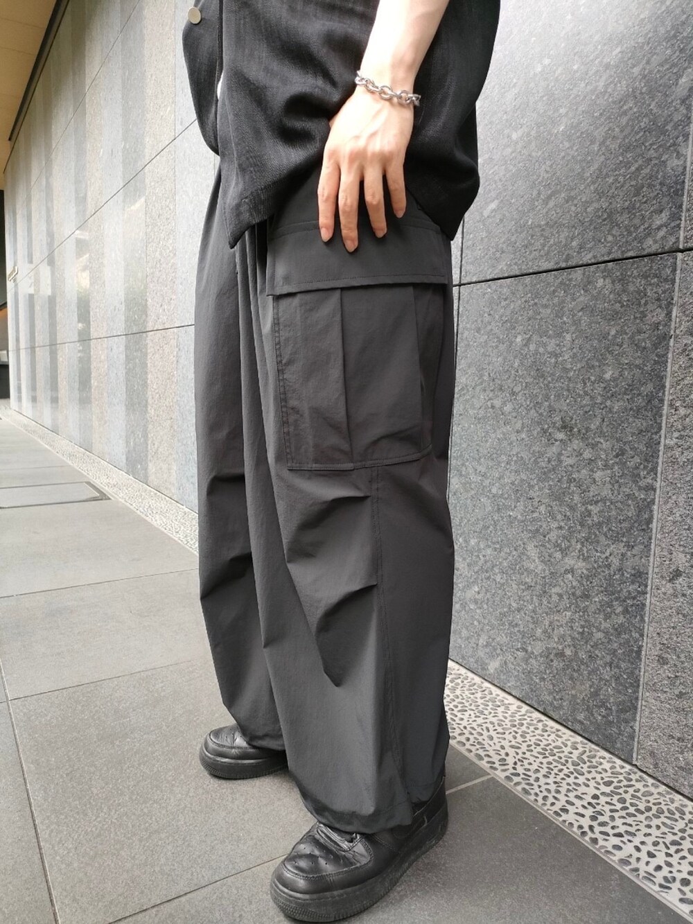 ブラック系のカーゴパンツ、ブラック系のベスト、ホワイト系のTシャツ/カットソーを着用したメンズの夏コーディネートの2枚目の写真