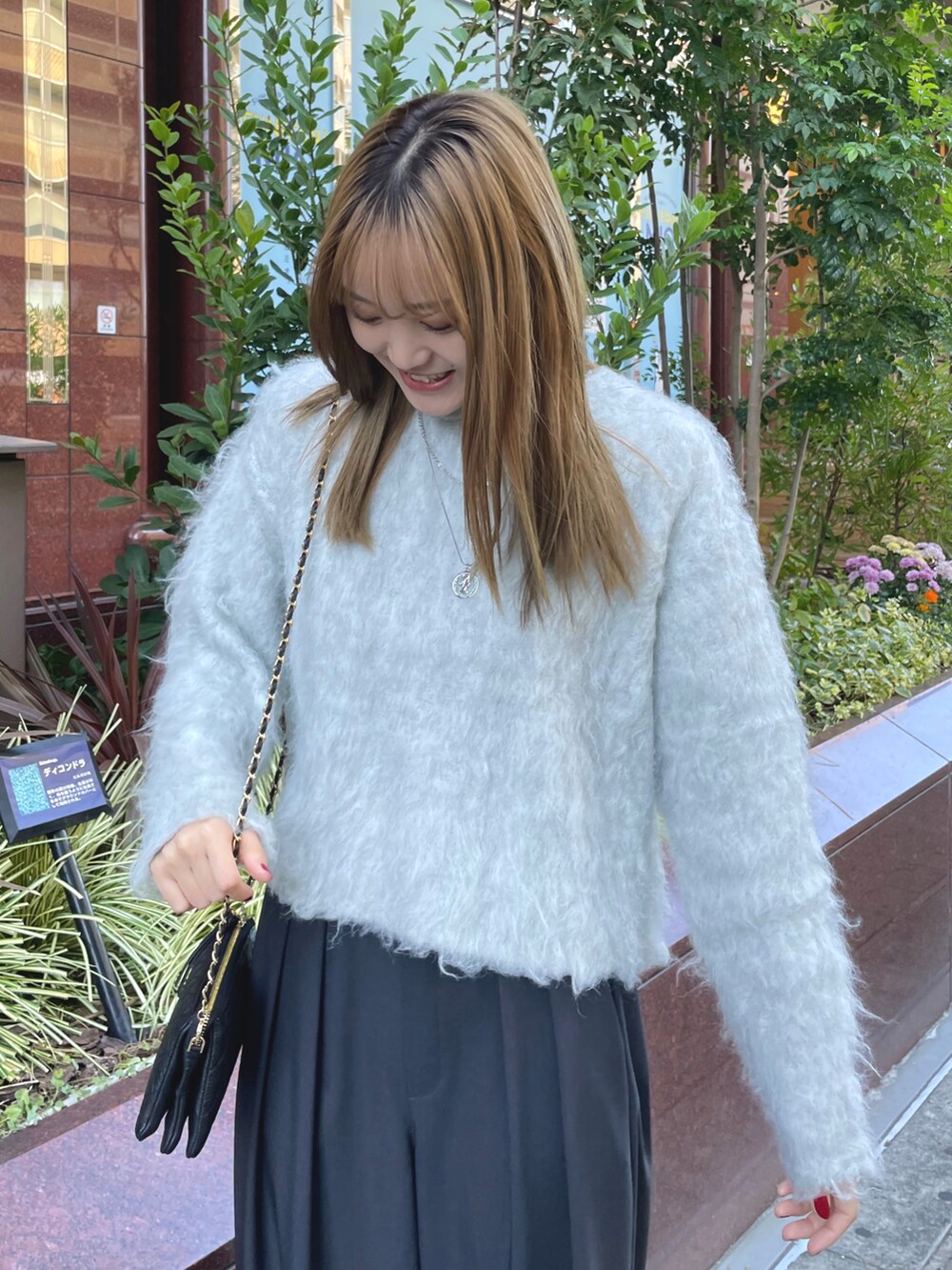 グレー系のニット/セーター、ブラック系のショルダーバッグ、ブラック系のスラックスを着用したレディースの秋コーディネートの5枚目の写真