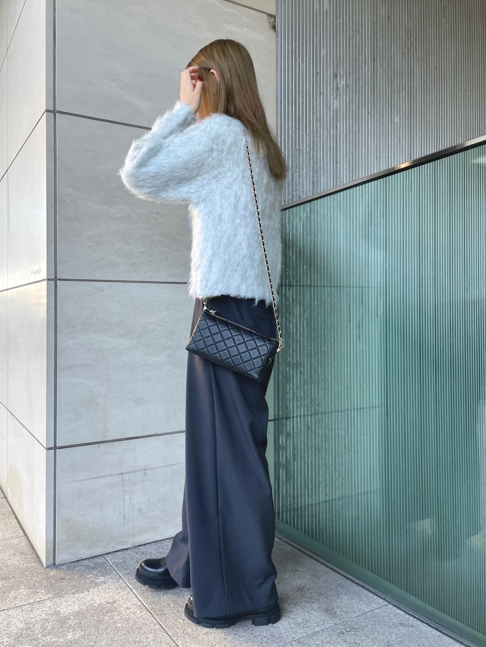 グレー系のニット/セーター、ブラック系のショルダーバッグ、ブラック系のスラックスを着用したレディースの秋コーディネートの3枚目の写真