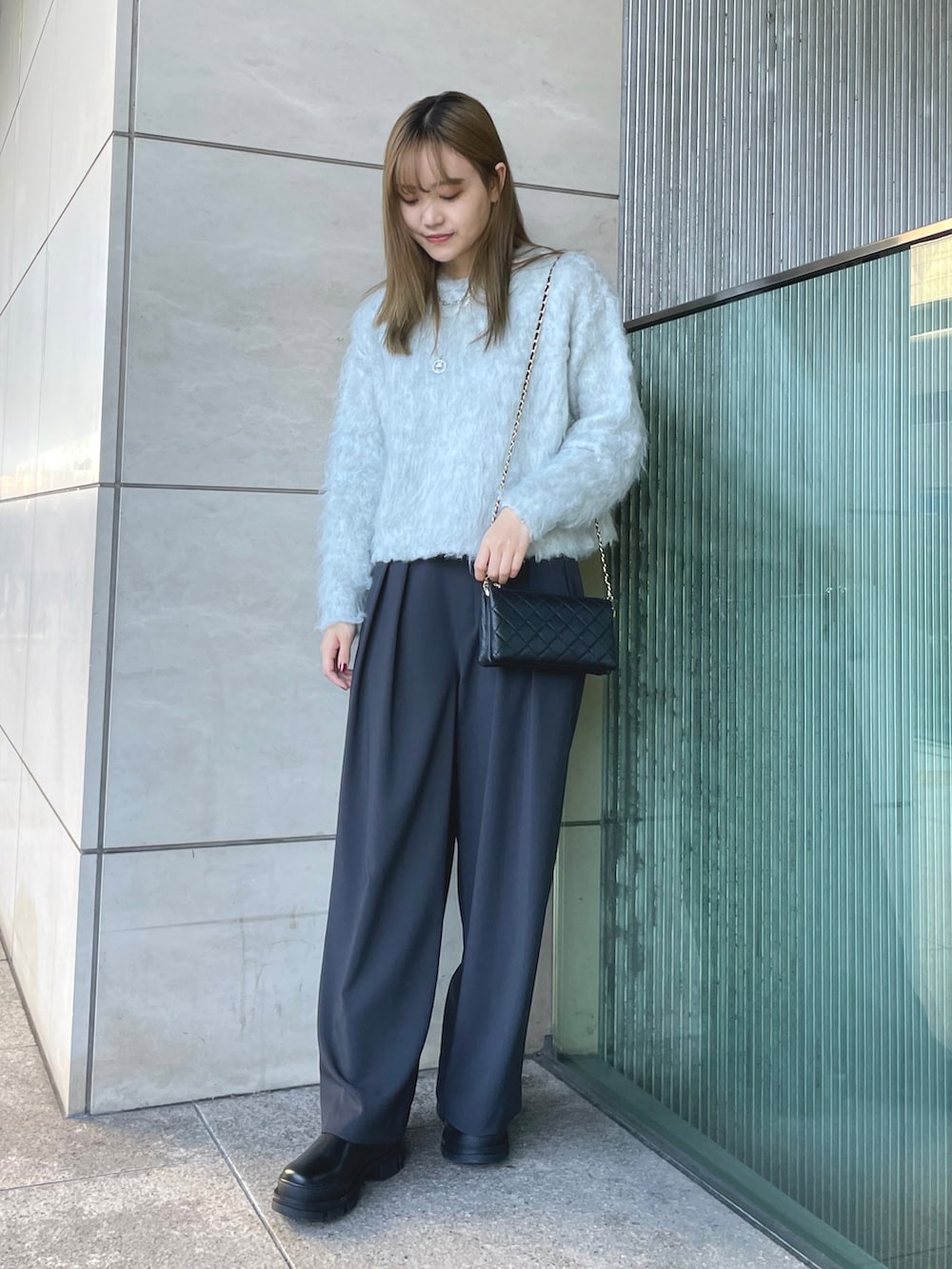 グレー系のニット/セーター、ブラック系のショルダーバッグ、ブラック系のスラックスを着用したレディースの秋コーディネートの2枚目の写真