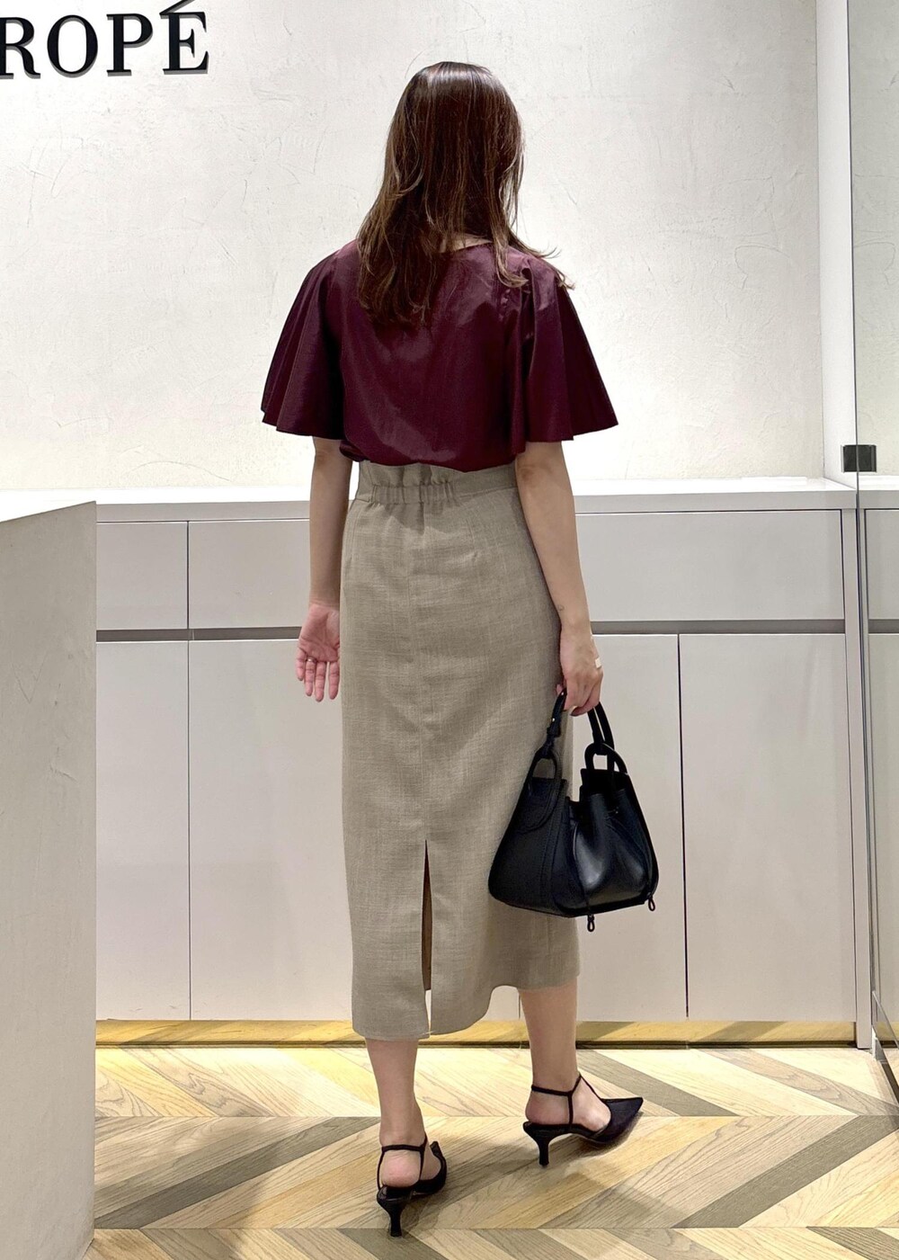 ブラック系のショルダーバッグ、ブラック系のパンプス、ベージュ系のスカートを着用したレディースの夏コーディネートの3枚目の写真