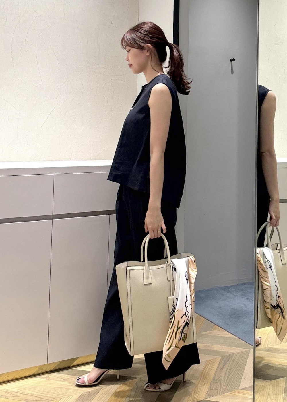 ベージュ系のトートバッグ、ホワイト系のサンダル、ブルー系のシャツ/ブラウスを着用したレディースの夏コーディネートの2枚目の写真