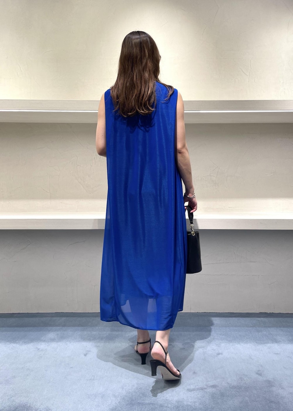 ブラック系のショルダーバッグ、ブルー系のワンピース、ブラック系のサンダルを着用したレディースの夏コーディネートの2枚目の写真