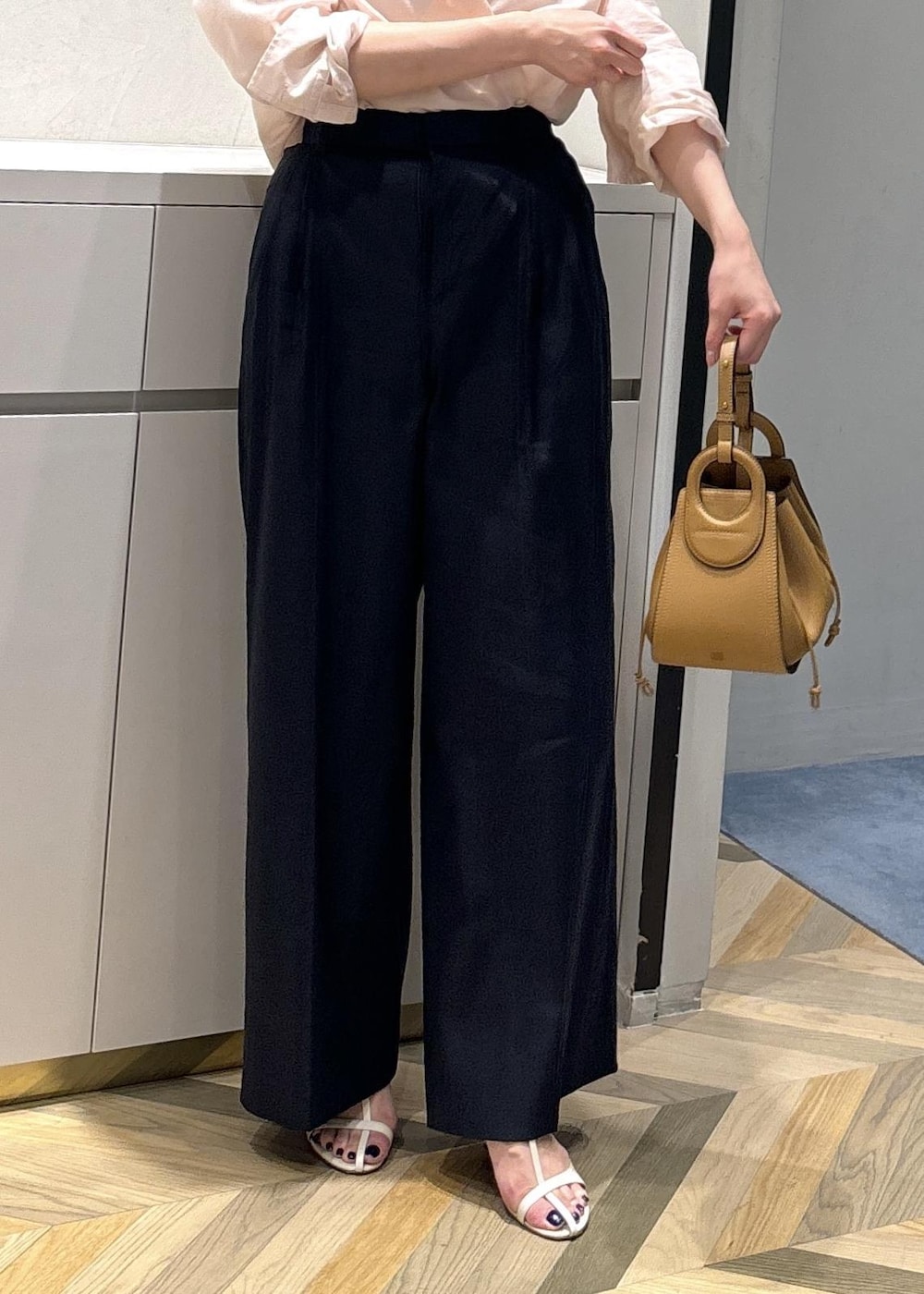 イエロー系のハンドバッグ、ホワイト系のサンダル、ホワイト系のタンクトップを着用したレディースの夏コーディネートの5枚目の写真