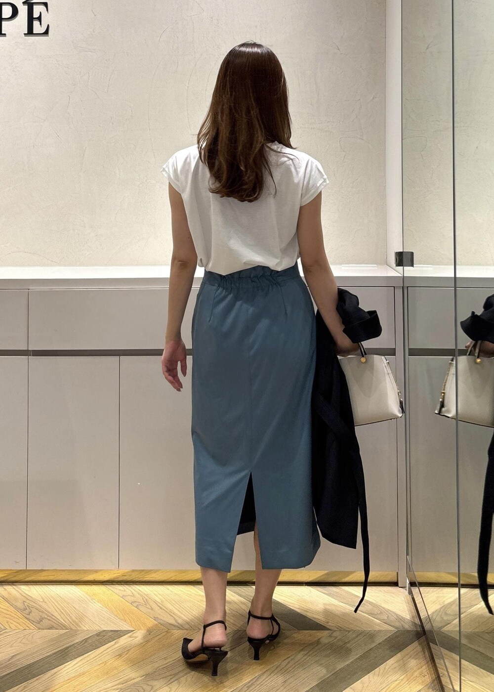 グレー系のハンドバッグ、ブラック系のパンプス、ブラック系のテーラードジャケットを着用したレディースの夏コーディネートの6枚目の写真