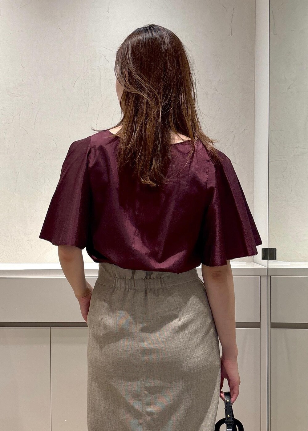 ブラック系のショルダーバッグ、ブラック系のパンプス、ベージュ系のスカートを着用したレディースの夏コーディネートの7枚目の写真