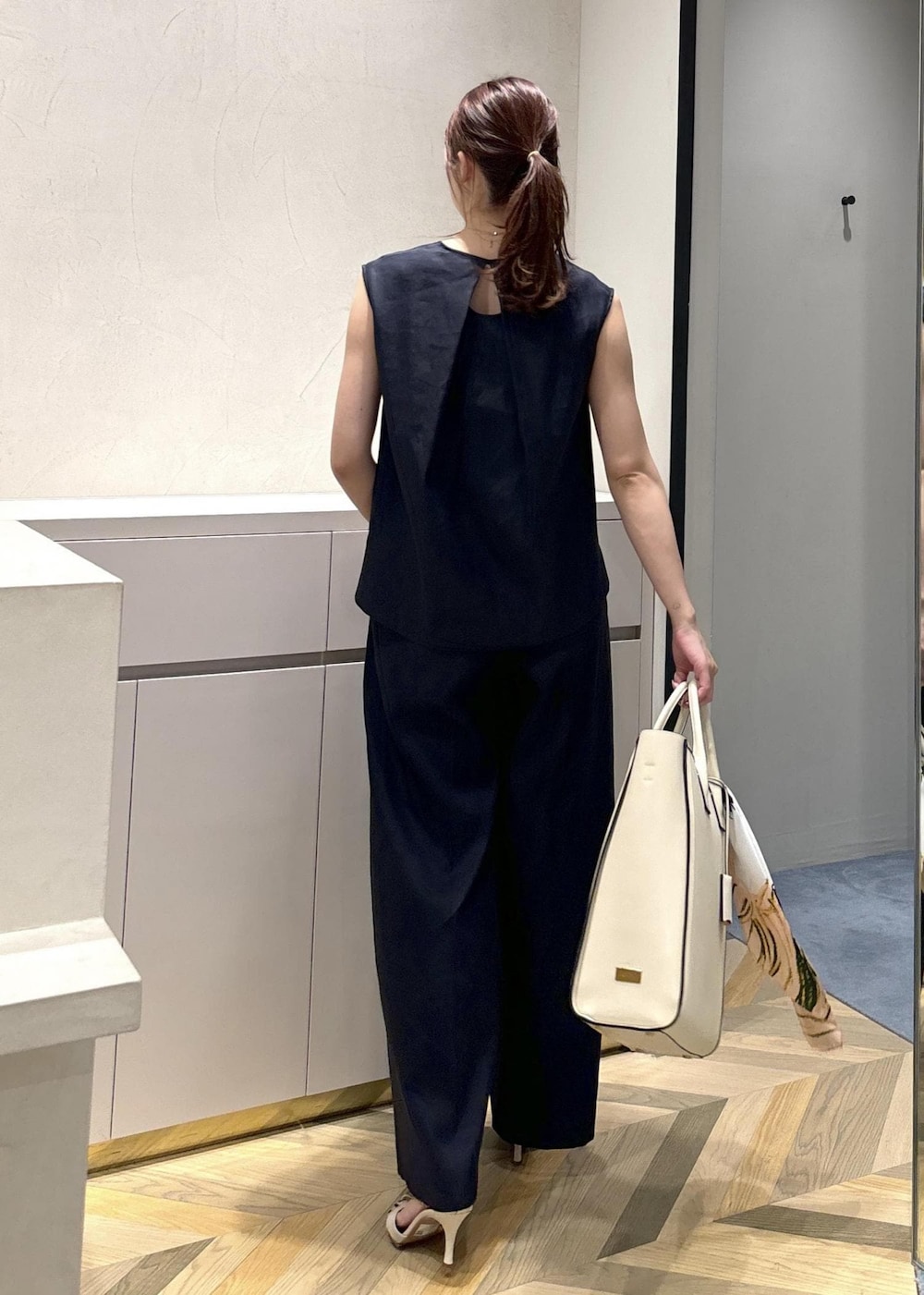 ベージュ系のトートバッグ、ホワイト系のサンダル、ブルー系のシャツ/ブラウスを着用したレディースの夏コーディネートの3枚目の写真