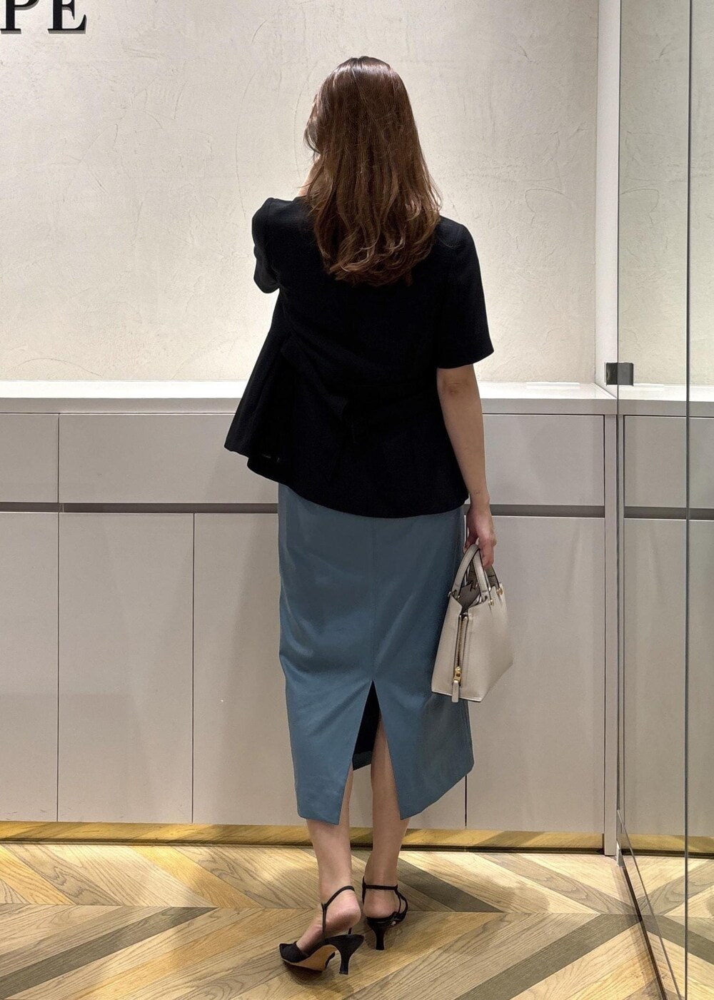 グレー系のハンドバッグ、ブラック系のパンプス、ブラック系のテーラードジャケットを着用したレディースの夏コーディネートの3枚目の写真