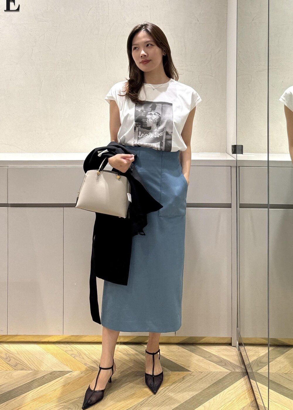 グレー系のハンドバッグ、ブラック系のパンプス、ブラック系のテーラードジャケットを着用したレディースの夏コーディネートの4枚目の写真